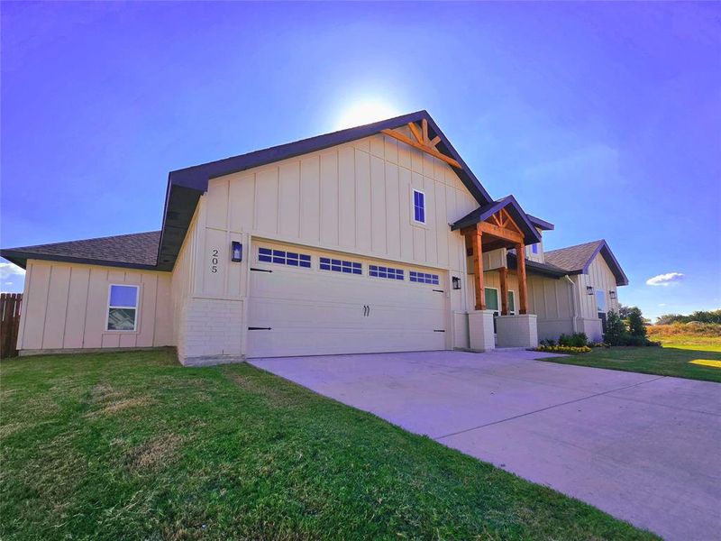 View of front of home featuring board and batten siding, a front lawn, a garage, and concrete driveway View of front of home featuring board and batten siding, a front lawn, a garage, and concrete driveway