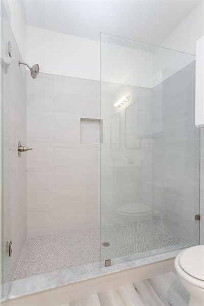 Bathroom featuring a shower with door and toilet