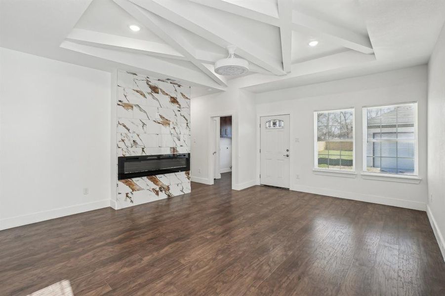 Unfurnished living room with beam ceiling and dark hardwood / wood-style flooring