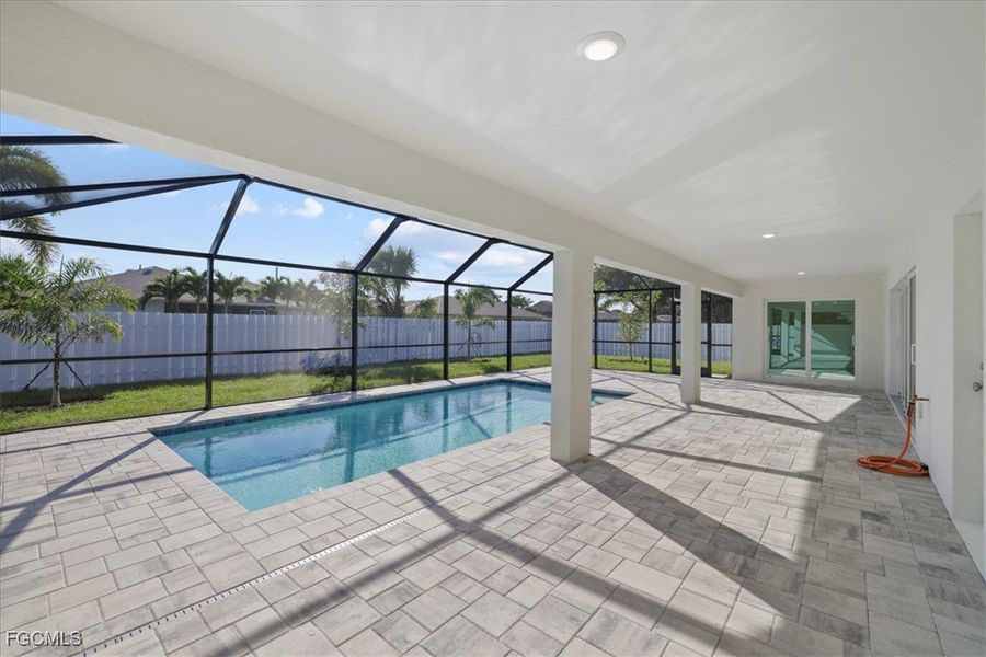 View of swimming pool with a sunroom, a fenced backyard, a patio, and glass enclosure