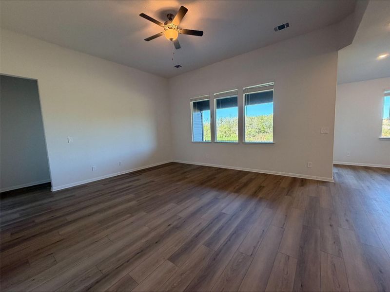 Unfurnished room with dark wood finished floors, healthy amount of natural light, and ceiling fan