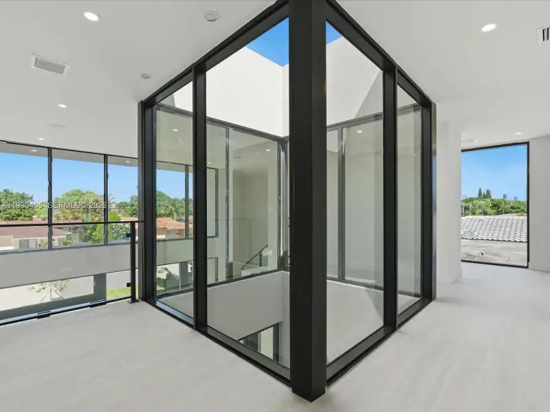 Central glass-encased atrium featuring floor-to-ceiling windows and metal framing, complemented by recessed lighting and neutral stone-finish flooring Central glass-encased atrium featuring floor-to-ceiling windows and metal framing, complemented by recessed lighting and neutral stone-finish flooring