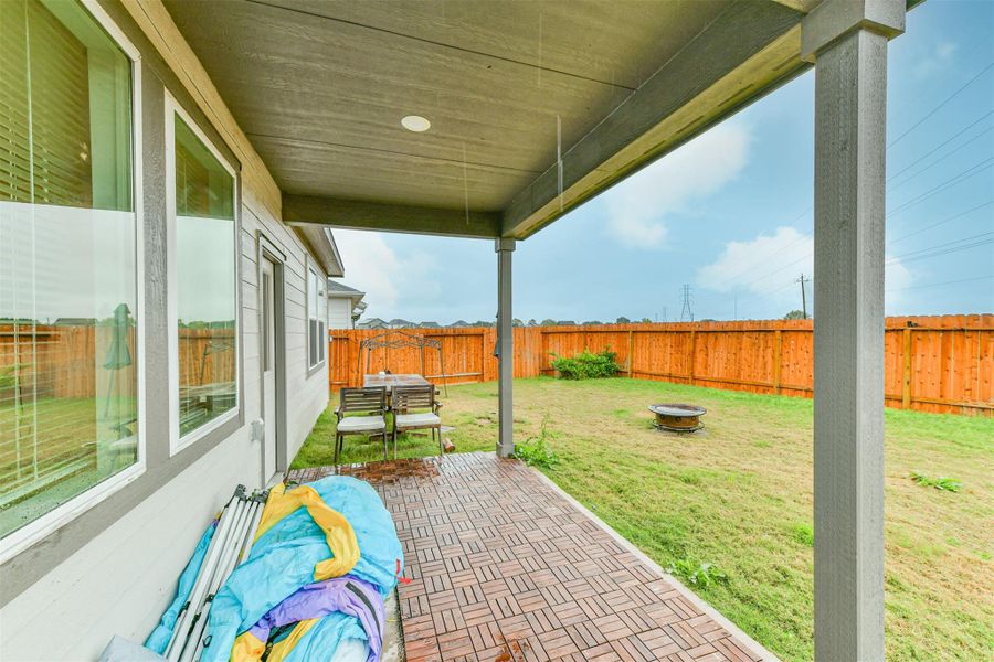 The covered patio is perfect for entertaining! The area is perfect for outdoor relaxation! No back neighbors! *the blow up house, chairs, table, fire pit and the wooden flooring will be removed*