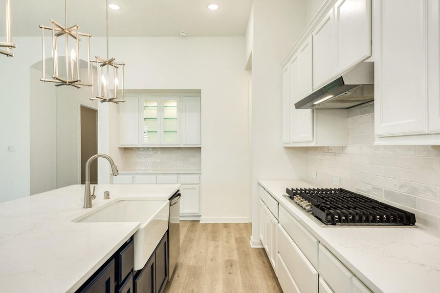 The bright white kitchen, featuring stunning quartz countertops, creates an inviting and functional space perfect for any aspiring chef.