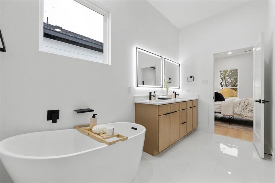 Ensuite bathroom featuring a freestanding tub, double vanity, and light tile patterned floors