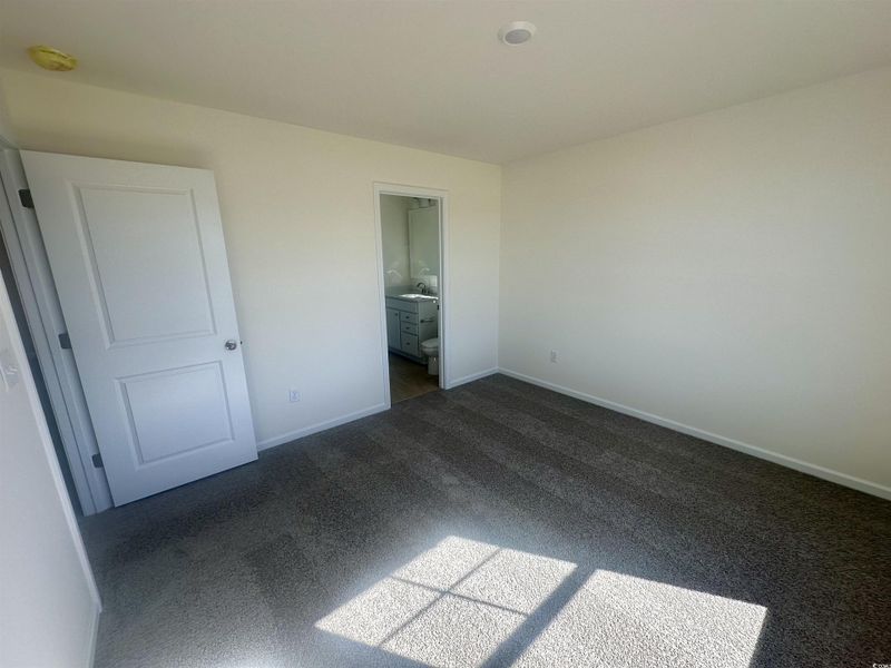 Unfurnished bedroom featuring carpet and connected bathroom Unfurnished bedroom featuring carpet and connected bathroom