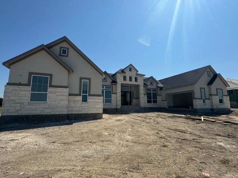 View of front of house featuring stone siding, a garage, and stucco siding