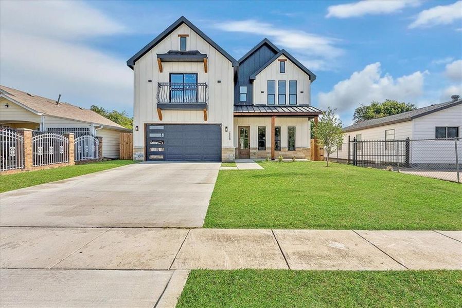 Modern inspired farmhouse with board and batten siding, concrete driveway, a garage, stone siding, and a gate