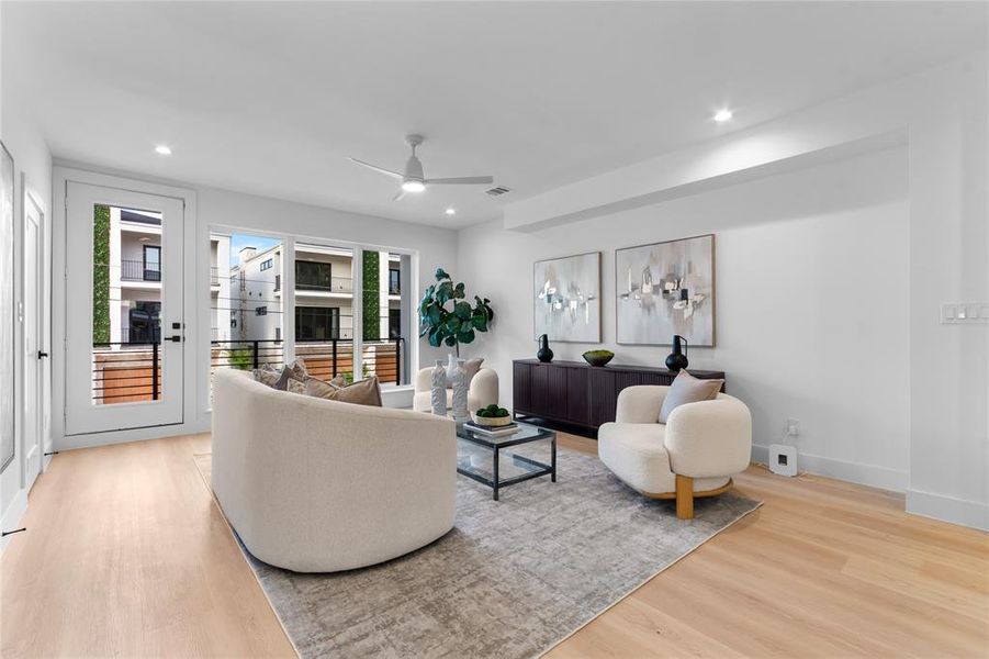 Spacious living area featuring light wood-finish flooring, recessed lighting, and a contemporary ceiling fan Spacious living area featuring light wood-finish flooring, recessed lighting, and a contemporary ceiling fan