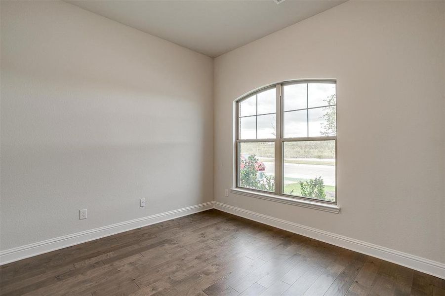 Unfurnished room featuring lofted ceiling and dark hardwood / wood-style flooring