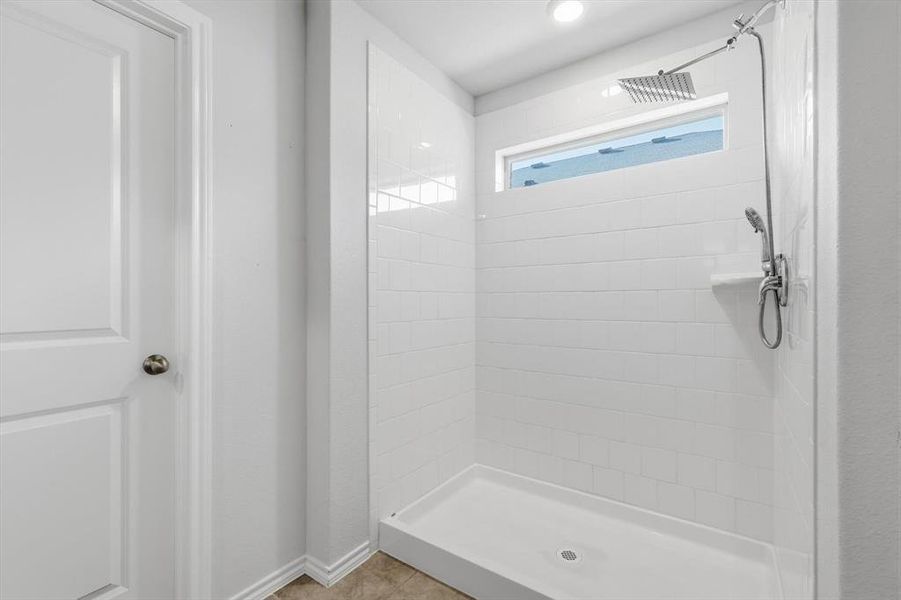 Bathroom featuring a shower stall and light tile patterned floors Bathroom featuring a shower stall and light tile patterned floors