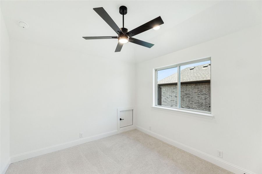 Empty bedroom with carpet, black ceiling fan, single window, and small access panel on wall
