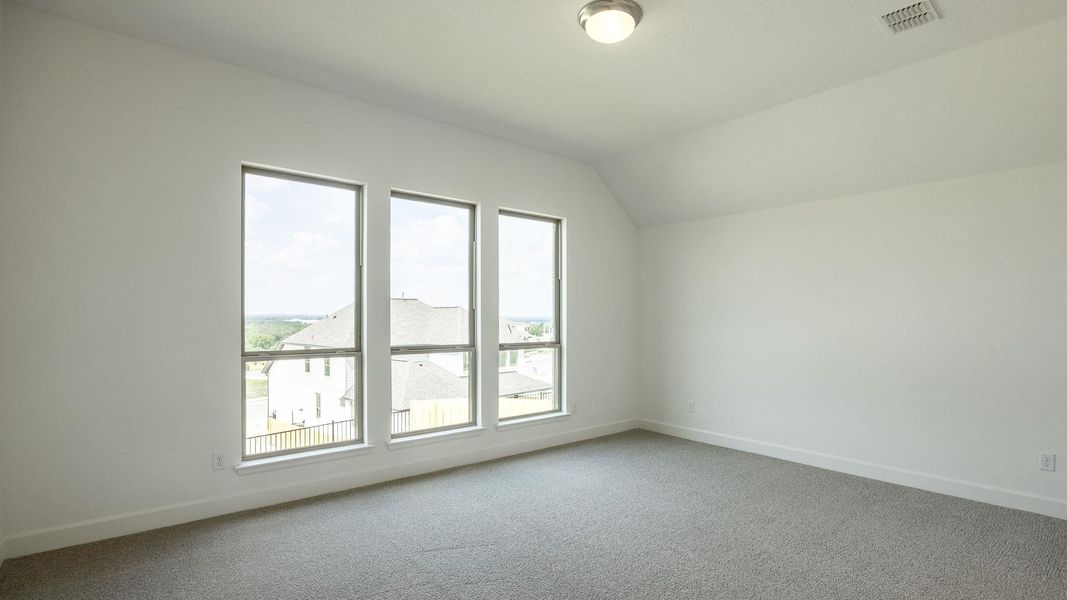 Empty room featuring carpet floors and vaulted ceiling