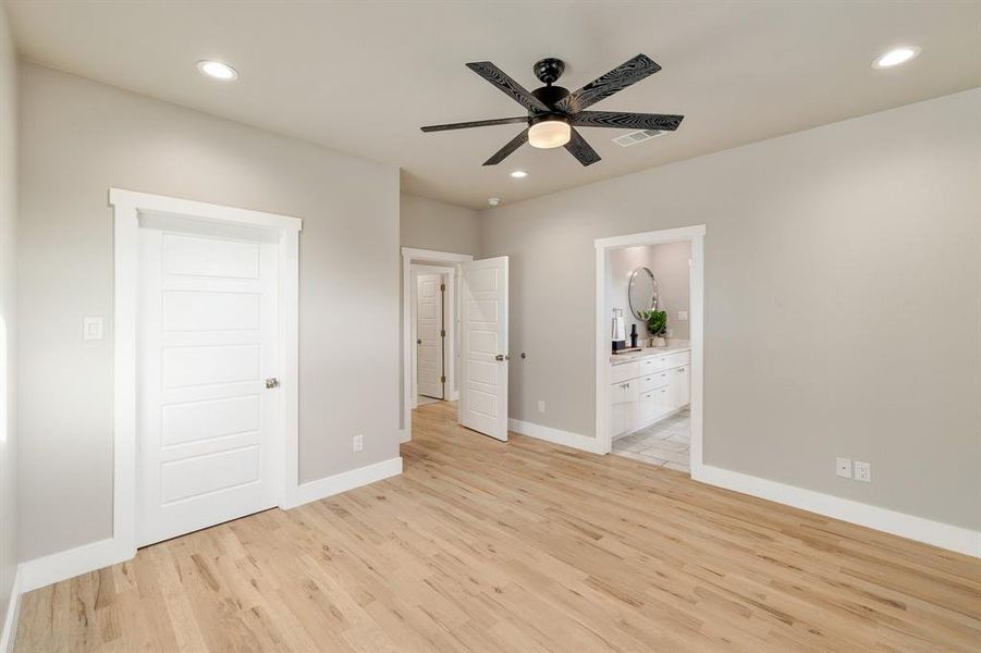 Unfurnished bedroom featuring ensuite bath, ceiling fan, and light hardwood / wood-style floors