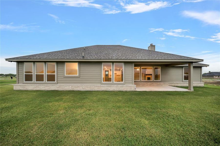 Back of property with a patio, a lawn, a chimney, and roof with shingles Back of property with a patio, a lawn, a chimney, and roof with shingles