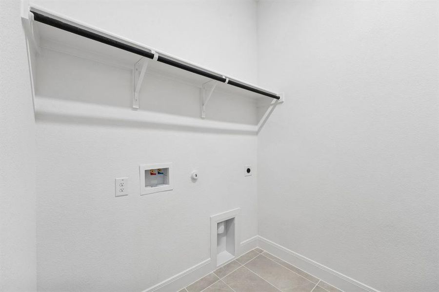 Laundry area with hookup for a gas dryer, light tile patterned flooring, hookup for a washing machine, and hookup for an electric dryer Laundry area with hookup for a gas dryer, light tile patterned flooring, hookup for a washing machine, and hookup for an electric dryer