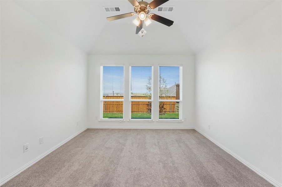 Empty room featuring light carpet, lofted ceiling, and ceiling fan