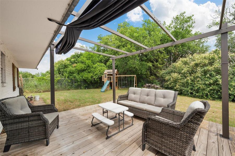 Wooden deck with an outdoor living space, a playground, and view of scattered trees Wooden deck with an outdoor living space, a playground, and view of scattered trees