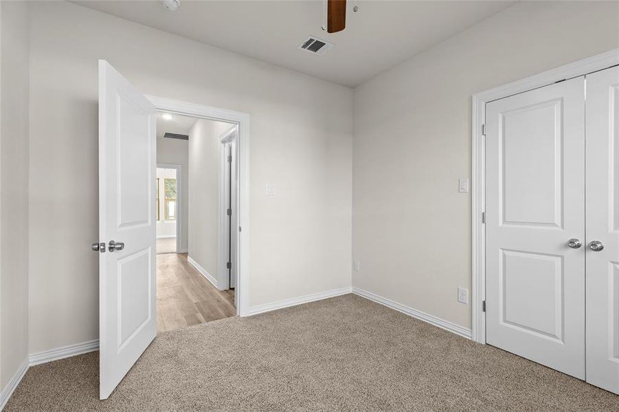 Unfurnished bedroom featuring carpet, ceiling fan, and a closet