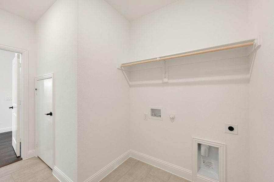 Laundry room with wall-mounted shelf, hanging rod, washer hookups, and gas dryer connection on white walls