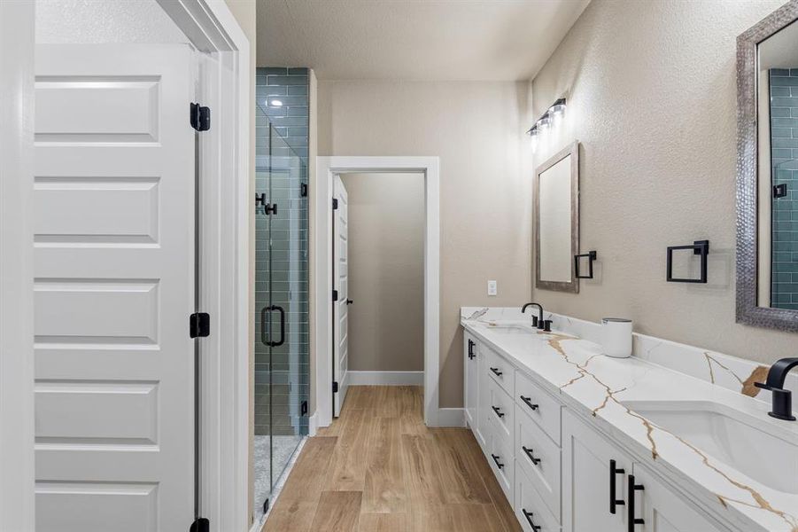 Bathroom featuring a double vanity with white cabinetry, integrated sinks, and a stone-finish countertop