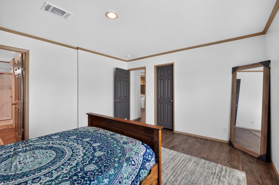 Well-lit sleeping quarters with rich wood-look flooring and easy access to an adjacent bathroom.