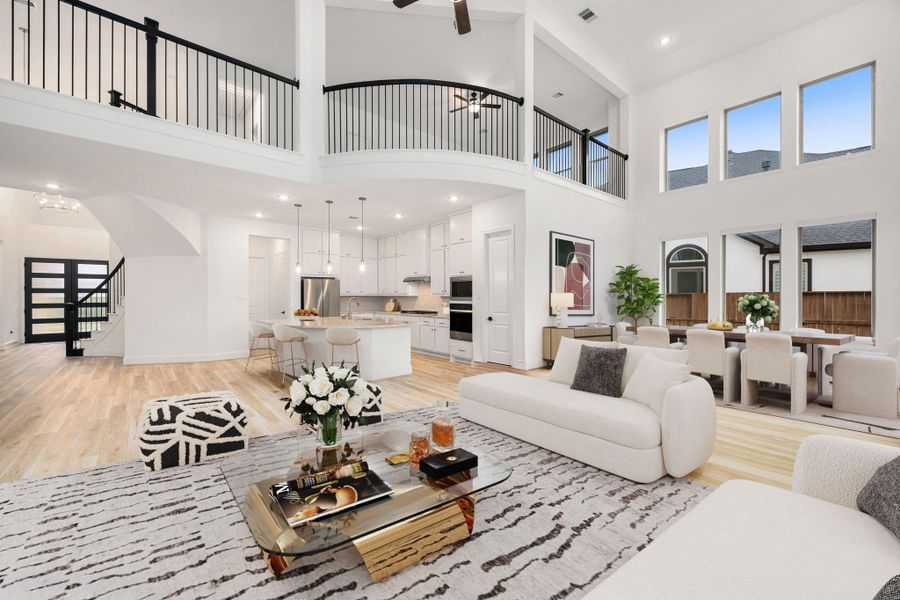 This light-filled living area features soaring ceilings, expansive windows, and an open-concept layout that flows seamlessly into the kitchen, creating an ideal space for both everyday living and entertaining.
