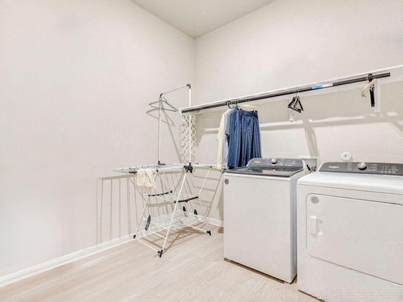 Functional laundry room equipped with contemporary appliances and practical hanging space.