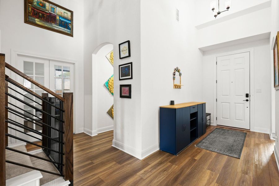 Entrance foyer with a high ceiling, arched walkways, stairs, and dark wood-style floors Entrance foyer with a high ceiling, arched walkways, stairs, and dark wood-style floors