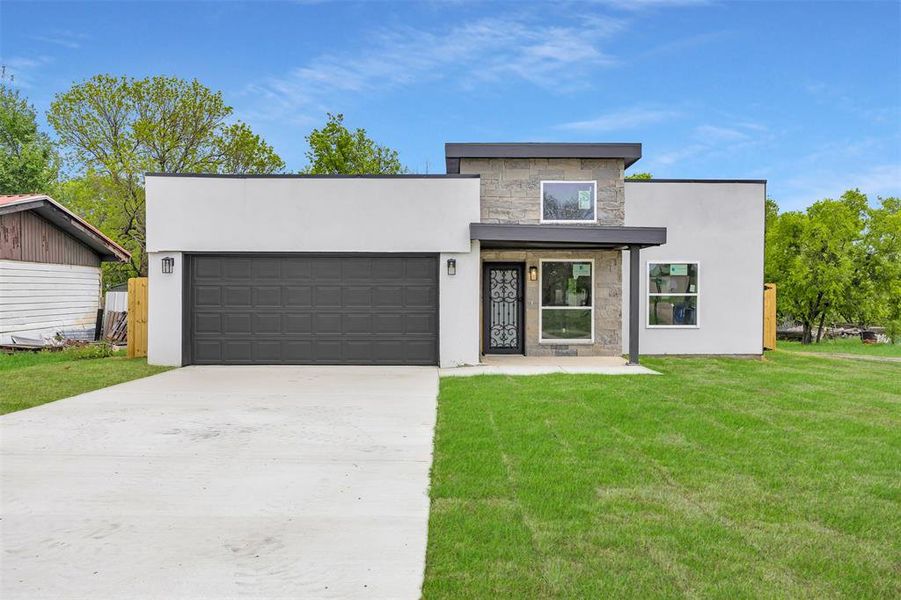 Modern home with a garage, driveway, stucco siding, and stone siding
