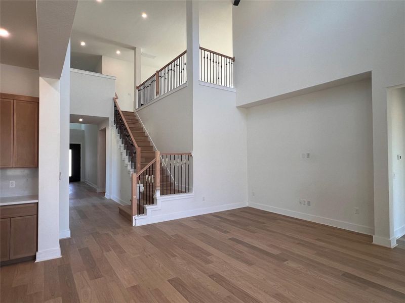 Unfurnished living room with a high ceiling, dark wood-style flooring, and recessed lighting
