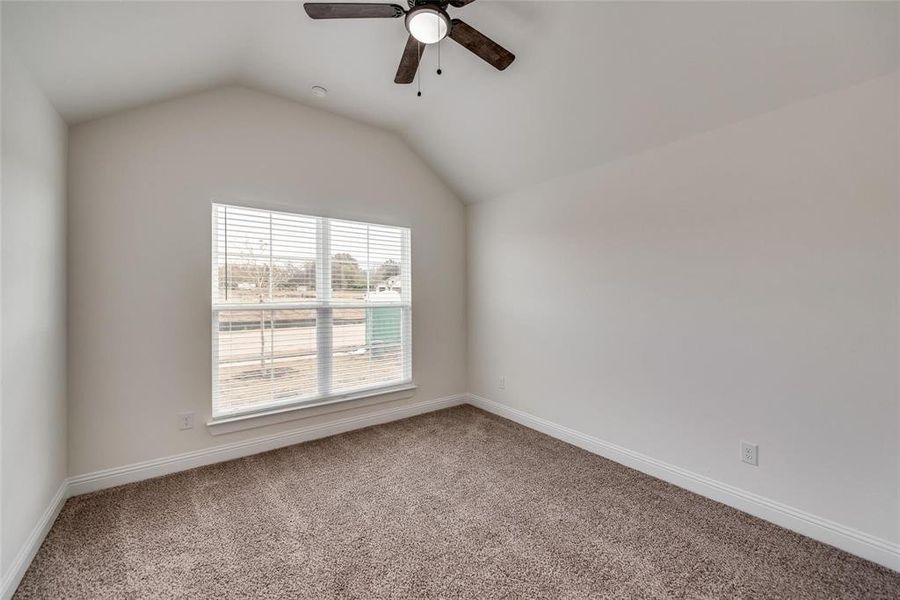 Spare room with carpet, vaulted ceiling, and ceiling fan