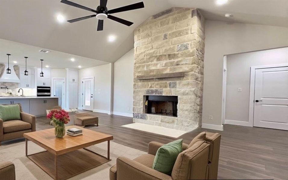 Living room featuring dark floors, a fireplace, high vaulted ceiling, ceiling fan, and recessed lighting