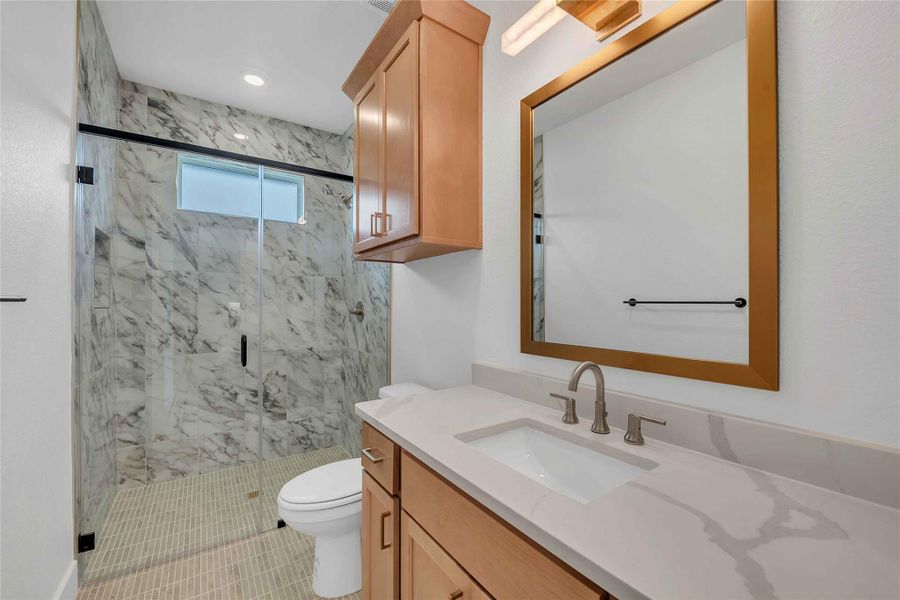 Bathroom featuring vanity, a marble finish shower, and toilet Bathroom featuring vanity, a marble finish shower, and toilet