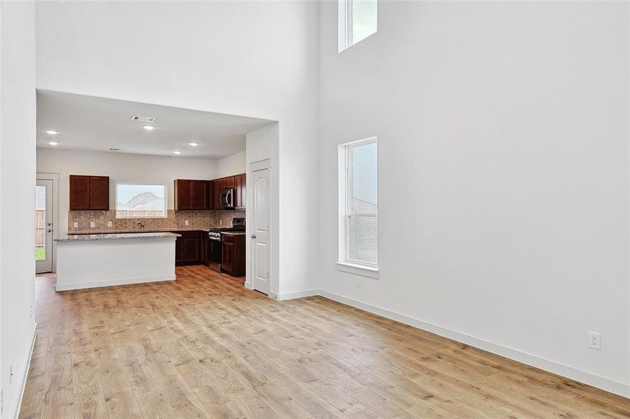 Kitchen with sink, light hardwood / wood-style flooring, decorative backsplash, appliances with stainless steel finishes, and dark brown cabinetry