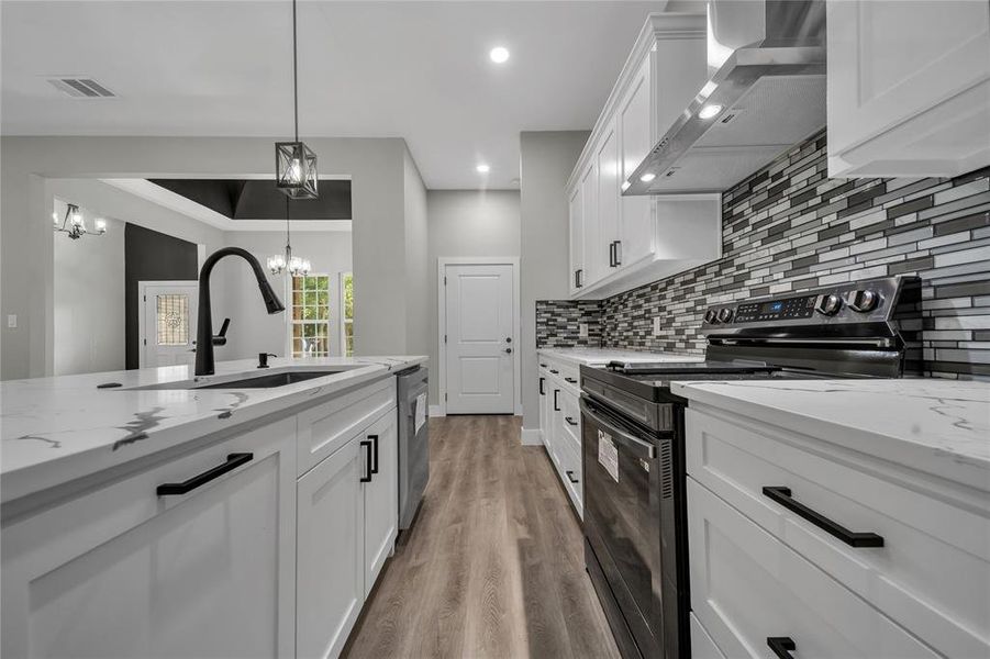 Kitchen with decorative light fixtures, wood-type flooring, tasteful backsplash, wall chimney exhaust hood, and black range with electric stovetop