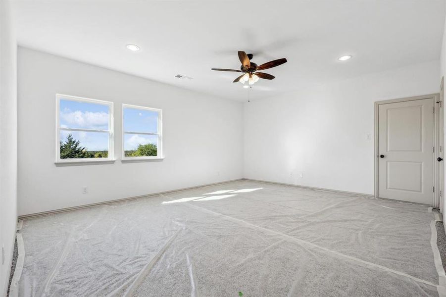 Carpeted empty room featuring ceiling fan and a baseboard radiator