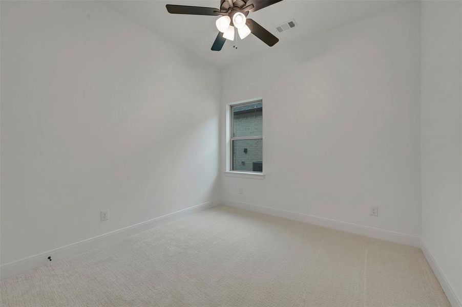 Neutral-toned carpeting paired with white walls, a single window, and a ceiling fan with integrated lighting