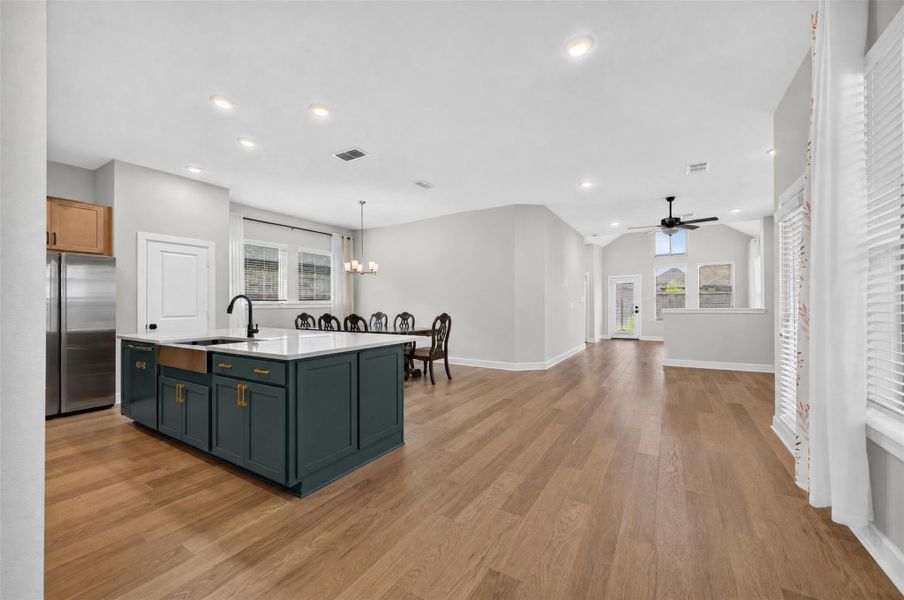 The open-concept kitchen and island with integrated sink serves as both a functional workspace and a natural gathering place. With uninterrupted views of the dining and living areas, it creates a seamless connection throughout the home's main living spaces, making everyday living, entertaining, and meaningful moments feel effortlessly connected.
