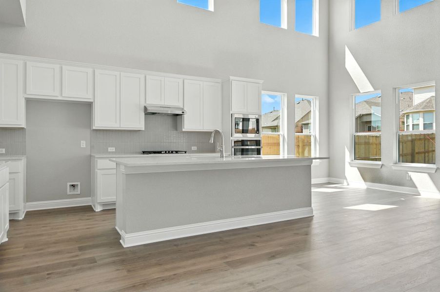 Kitchen with white cabinetry, plenty of natural light, tasteful backsplash, and a high ceiling