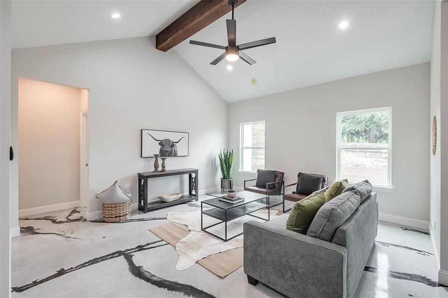 Living room with high vaulted ceiling, beamed ceiling, ceiling fan, and a wealth of natural light