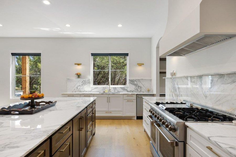 A well-lit kitchen with a spacious island, stainless steel appliances, and elegant marble countertops. A well-lit kitchen with a spacious island, stainless steel appliances, and elegant marble countertops.