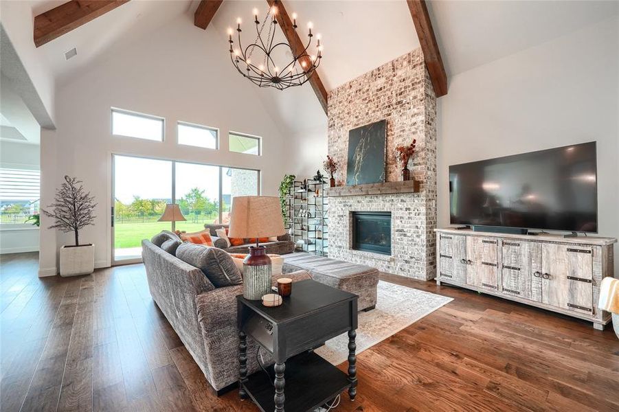 Living room with hanging lights, dark wood-style flooring, a fireplace, and healthy amount of natural light