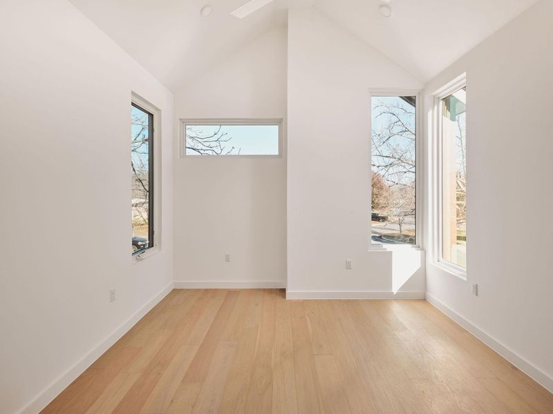 Unfurnished room with light wood-style floors and lofted ceiling
