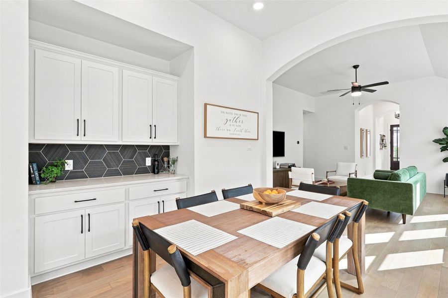 An arched doorway connects the casual dining area with built-in cabinetry to the main living space.