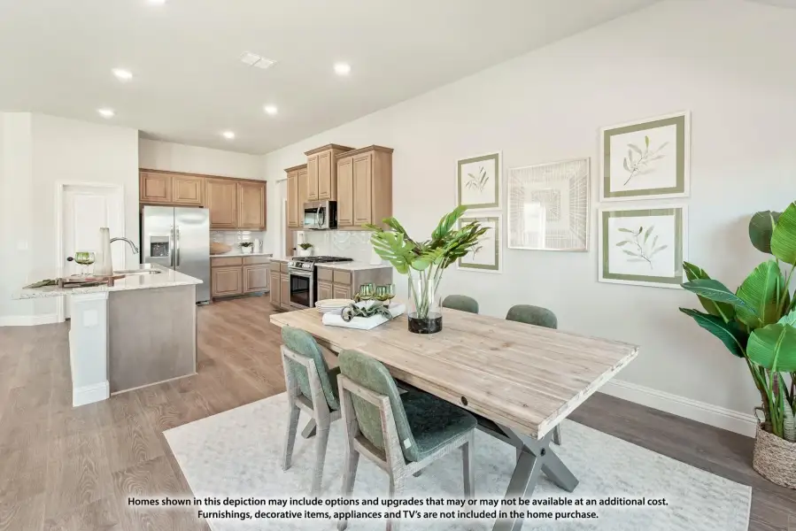 Open dining area with wood table and green chairs, connected to kitchen with tan cabinets and stainless appliances