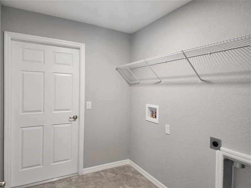 Laundry room off of the garage with washer and dryer hook-ups and shelving for storage