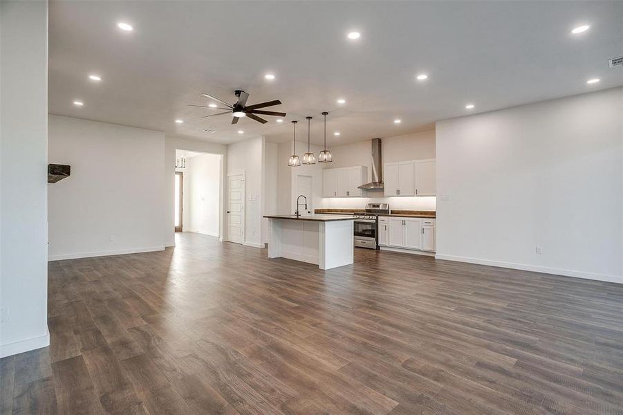 Unfurnished living room featuring sink, ceiling fan, and dark hardwood / wood-style floors