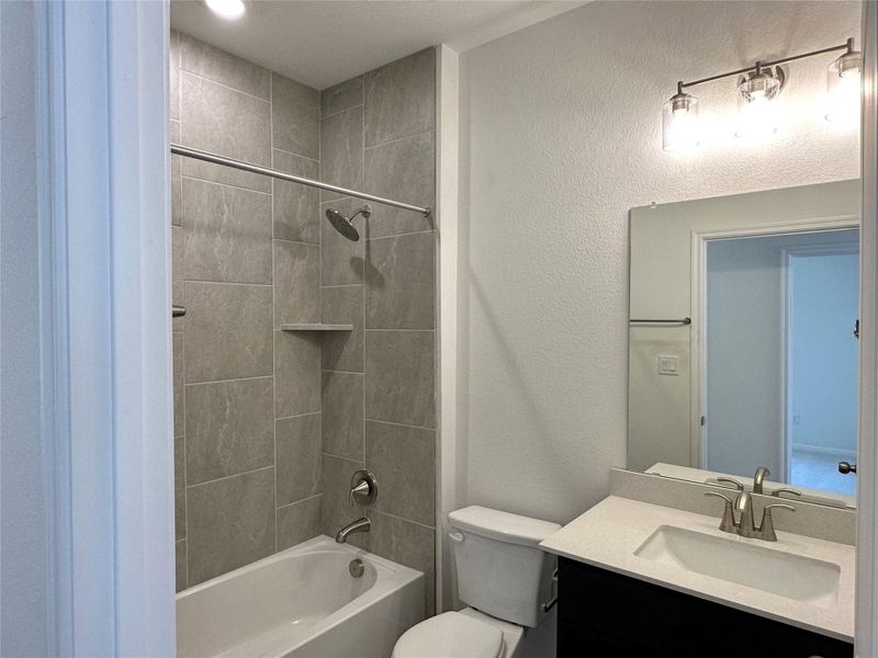 Bathroom featuring vanity, a textured wall, and bathing tub / shower combination