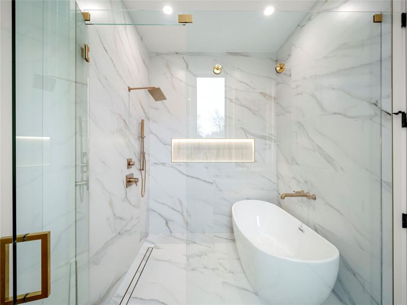 Bathroom with a freestanding tub and a marble finish shower